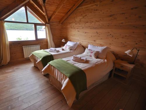 a bedroom with two beds in a log cabin at Aguas Arriba Lodge in El Chalten