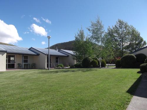 a house with a large lawn in front of it at Ahuriri Motels in Omarama