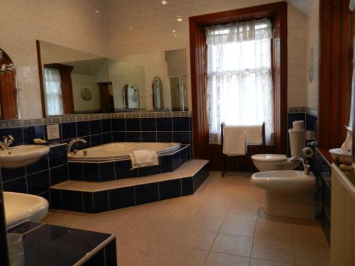 a bathroom with two sinks, a toilet and a bath tub at Mansfield Castle Hotel in Tain
