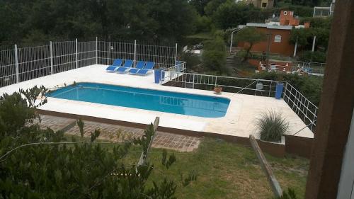 una piscina con sillas azules junto a una valla en Aires de San Antonio en San Antonio de Arredondo
