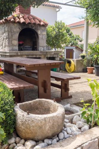 a picnic table and a pizza oven in a yard at Apartmani Pina in Krk