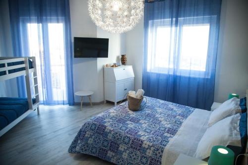 a bedroom with blue curtains and a bed and a chandelier at La Terrazza di Empedocle in Agrigento