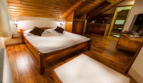 a bedroom with a bed with white sheets and wooden floors at Penzión Gitka in Vrútky