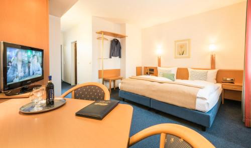 a hotel room with a large bed and a table with a table at Hotel Monika in Büttelborn