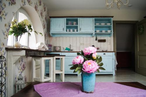 a vase with pink flowers on a table in a kitchen at Kalvín Restaurant & Pension in Rastislavice