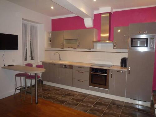 トゥールニュにあるTOURNUS Belle maison vue sur Saôneのピンクの壁のキッチン(テーブル、冷蔵庫付)