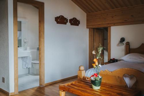 a bedroom with a bed and a table and a bathroom at Hôtel Magrappé in Veysonnaz
