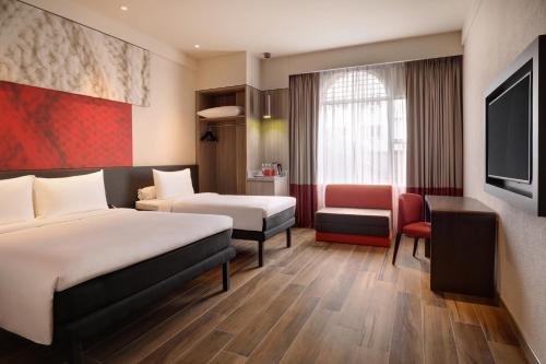 um quarto de hotel com duas camas e uma televisão em Ibis Melaka em Malaca