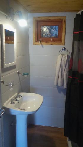 a bathroom with a white sink and a mirror at Las Huellas Cabaña in Balneario Pehuén-Có