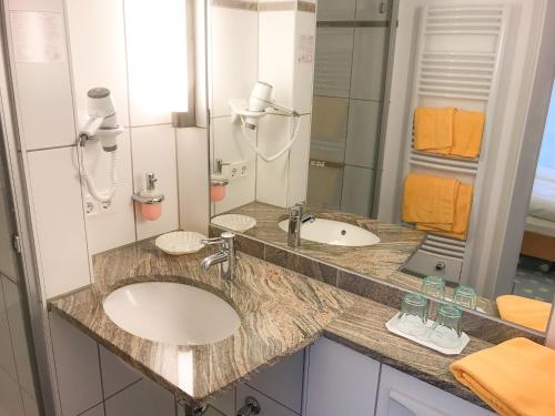 a bathroom with a sink and a mirror at Hotel Birkenhof in Hanau am Main