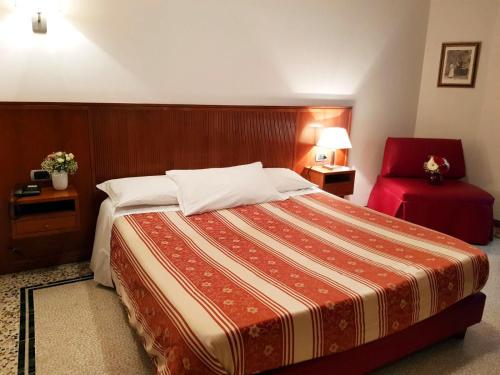a bedroom with a large bed and a red chair at Hotel Nappo in San Marzano sul Sarno