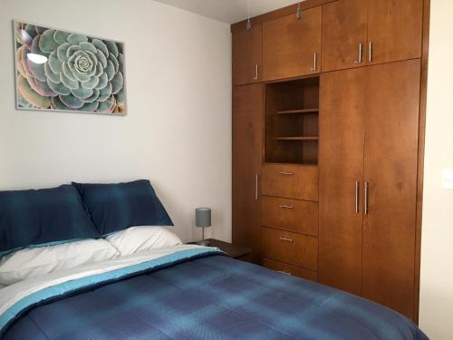 a bedroom with a blue bed and wooden cabinets at Fantastic & Cozy #4: Condo Close to the Beach in Ensenada
