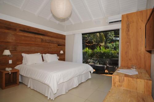a bedroom with a white bed and a large window at Rio Búzios Boutique Hotel in Búzios
