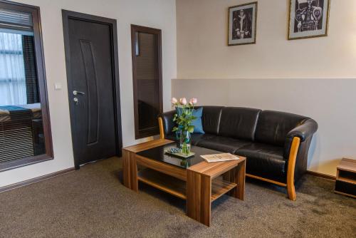 a living room with a black leather couch and a coffee table at Park-Hotel Yambol in Yambol