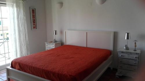 a bedroom with a red bed with two dressers and a window at Navegante's House in Almograve