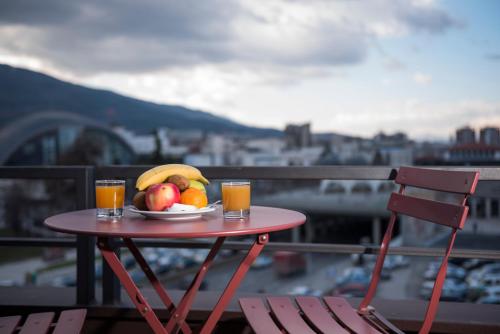 a table with a plate of fruit and two glasses of orange juice at Hotel Super 8 in Skopje