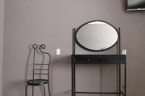 a mirror on a black stand next to a chair at Casa Zapopan Hotel in Guadalajara
