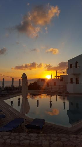 an umbrella sitting next to a swimming pool with the sunset at Amazones Village Suites in Hersonissos