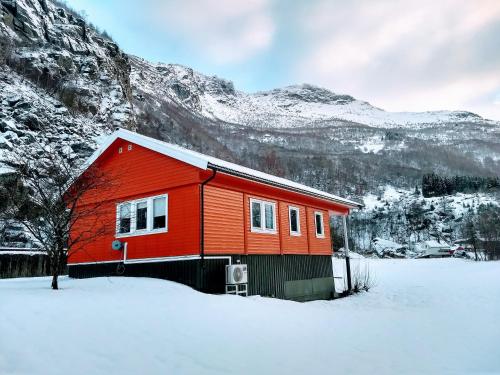 a red house in the snow in front of a mountain at Steinshølen Holiday Home in Flåm