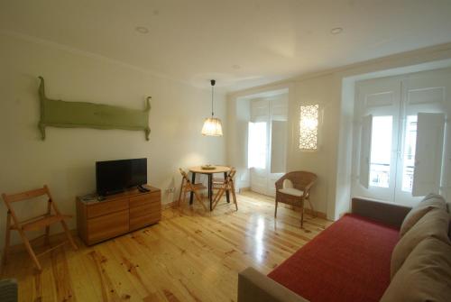 a living room with a tv and a table with chairs at My Mouraria Suites in Lisbon