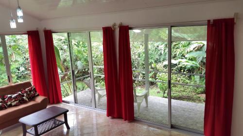 a living room with red curtains and a couch at Tropical Paradise Bungalows in Pital