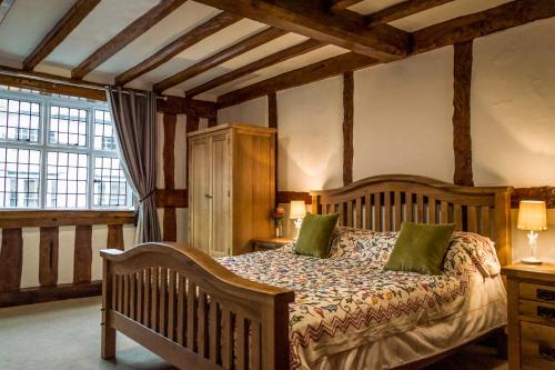 1 dormitorio con cama de madera y almohadas verdes en The Three Gables en Stratford-upon-Avon