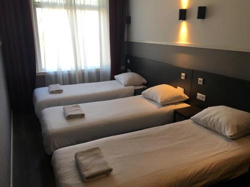a hotel room with three beds with towels on them at Hotel Manofa in Amsterdam