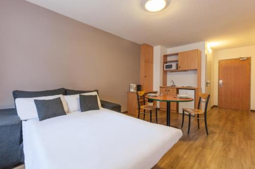 1 dormitorio con cama, mesa y cocina en City Residence Access Strasbourg en Estrasburgo