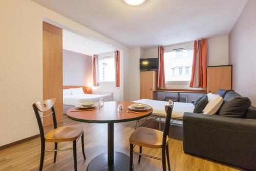 uma sala de estar com uma mesa e um sofá em City Residence Access Strasbourg em Estrasburgo