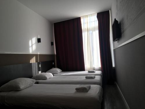 3 camas en una habitación de hotel con ventana en Hotel Manofa, en Ámsterdam
