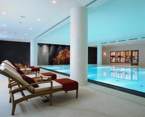 a pool in a hotel with chairs and a table at Rocco Forte The Charles Hotel in Munich