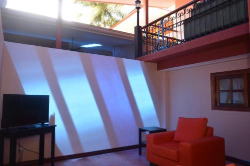 a living room with a red chair and a staircase at Hotel Castillo in San José