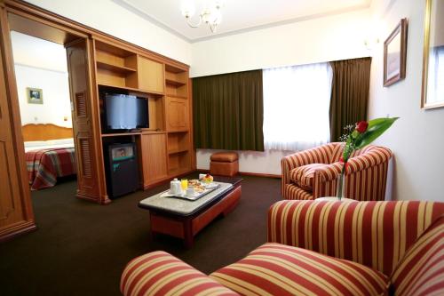 Habitación de hotel con 2 sillas, mesa y TV en Hotel Riogrande - Habilitado en Santa Fe