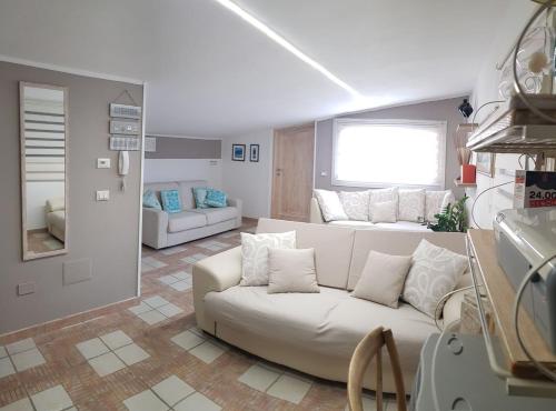 een woonkamer met een witte bank en een raam bij Appartamento mansardato Anda&Torra in Castelsardo