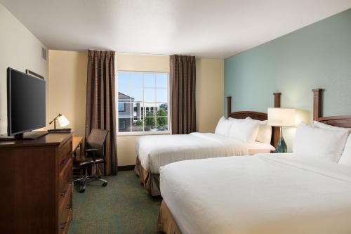 a hotel room with two beds and a flat screen tv at Staybridge Suites Sacramento-Folsom, an IHG Hotel in Folsom