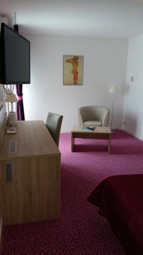 a room with a tv and a chair and a table at Les Balcons Du Velay in Monistrol-sur-Loire