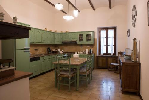 une cuisine avec des placards verts et une table avec des chaises dans l'établissement Villa al Castello Florence View, à Calenzano