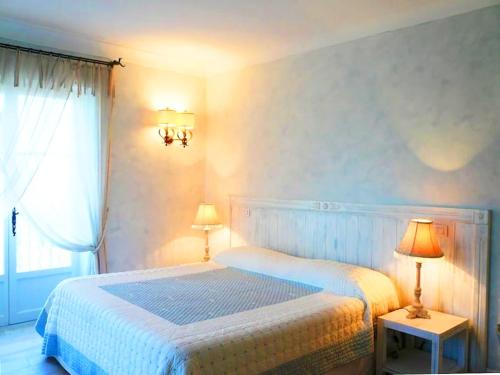 a white bedroom with a bed and two lamps at Villa Virginie in Saint-Tropez