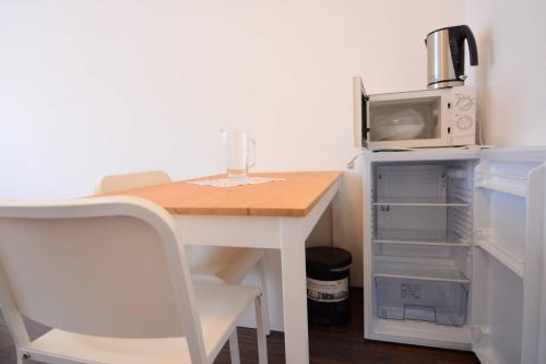 a small white table with a microwave and a refrigerator at Private rooms next to subway in Nürnberg