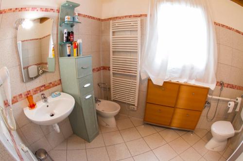 a bathroom with a sink and a toilet and a mirror at Dogana Vecchia - Hotel & Residence B&B Ristorante & Pizzeria in Trivignano Udinese