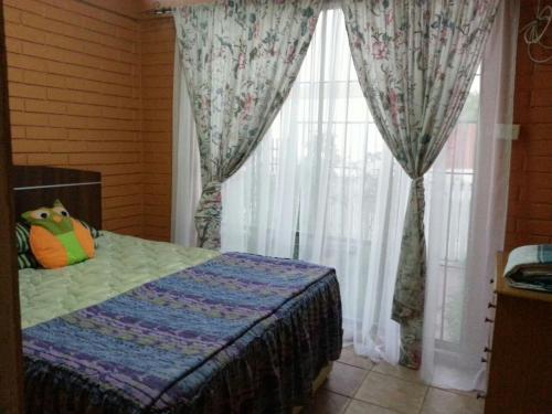 a bedroom with a bed and a window with curtains at Hostal Los Nogales in Coquimbo