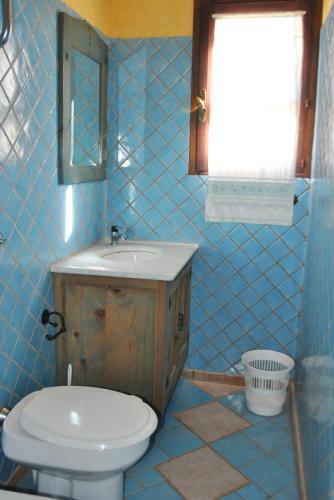 a blue tiled bathroom with a toilet and a sink at Principessa de Navarra in Santa Maria Navarrese
