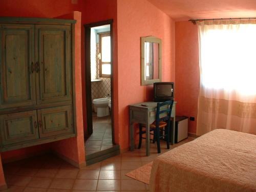 a bedroom with a bed and a desk and a mirror at Principessa de Navarra in Santa Maria Navarrese