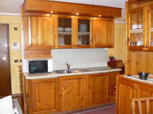 a kitchen with wooden cabinets and a sink and a microwave at Charme a Cervinia Downtown Ski in-Ski out in Breuil-Cervinia