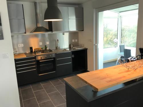 a kitchen with black cabinets and a wooden table at Maison de la Roche du Feu jusqu'à 12 personnes in Gouézec