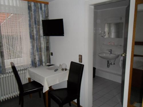 Habitación con mesa, sillas y lavabo. en Hotel Gasthof Traube, en Kernen