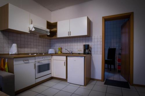 eine kleine Küche mit weißen Schränken und einem Waschbecken in der Unterkunft Ferienwohnung Scheid in Lahr