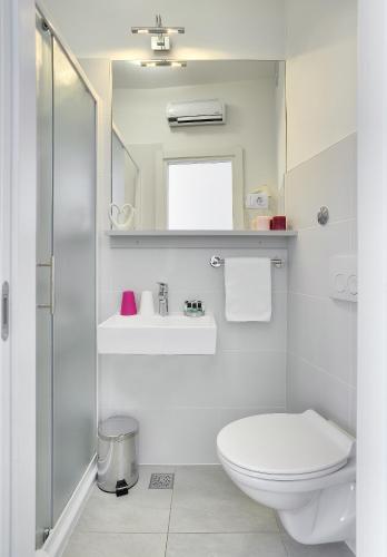 a white bathroom with a toilet and a sink at Boutique Suites Joyce in Pula
