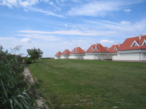 a row of buildings with red roofs and a grass field at Gólya Villa Park in Velence