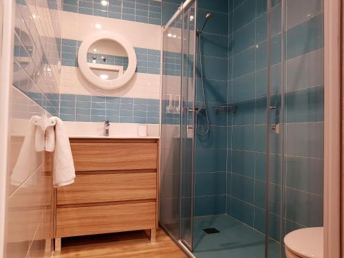 y baño de azulejos azules con ducha y lavamanos. en Avenida De America Tijcal, en Madrid